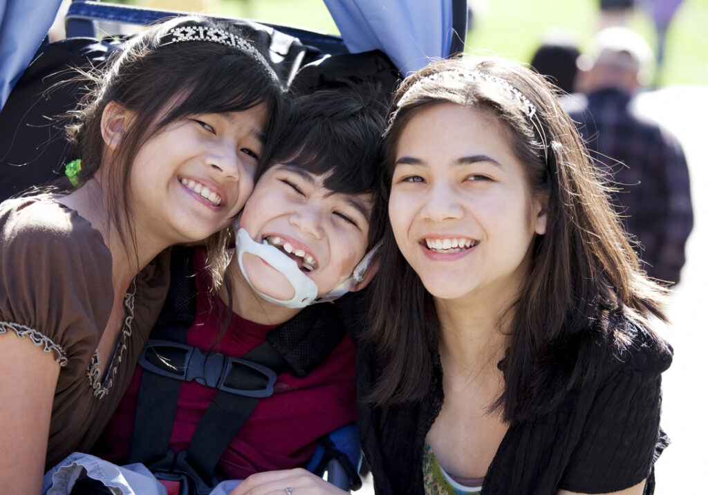 Two sisters hugging their brother with a disability
